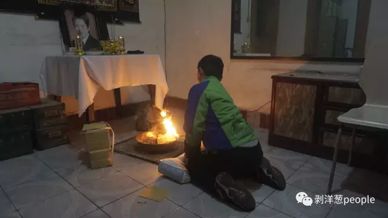 2月19日晚，死者姚永胜12岁的儿子跪在出租屋搭设的灵位前烧纸钱。