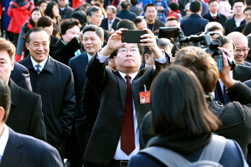 3月5日上午,十二届全国人大五次会议开幕前,丁列明步入会场时用手机拍摄。记者张哲 摄