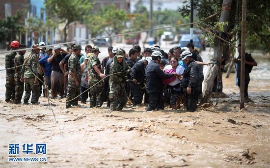 3月17日，在秘鲁利马，警察帮助民众穿过一条河水泛滥的街道。受“沿海厄尔尼诺现象”影响，秘鲁全国11个省普降暴雨，造成山洪暴发、河水泛滥，许多地方发生泥石流。据统计，秘鲁全国2017年以来已发生227起山体滑坡灾害，多处公路、民房被泥石流冲毁或覆盖，大片农作物被水淹没。新华社/路透