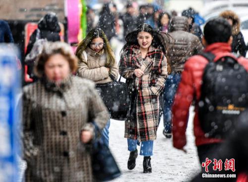 3月20日，受冷空气影响，新疆乌鲁木齐市降下纷纷扬扬的雪花，气温也随之骤降。图为民众冒雪出行。 中新社记者 刘新 摄