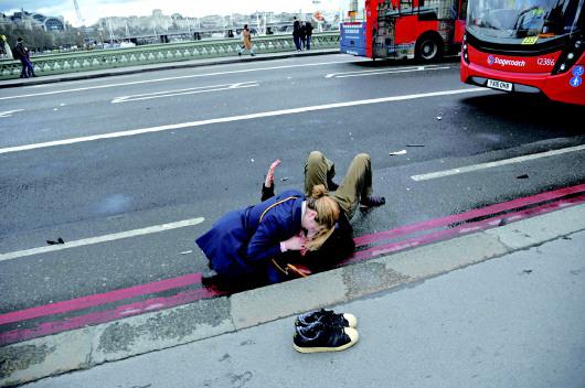 22日，在英国伦敦，一名女子在救治一名伤者。 新华/路透