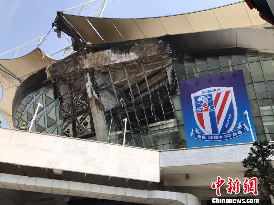 上海虹口足球场顶部的一块顶棚已被烧至脱落,建筑物内部的钢筋结构已清晰可见,上海申花队的宣传旗帜未受火势影响。 王子涛 摄