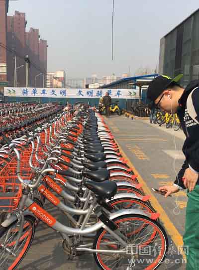 图为一行人正在用手机扫描摩拜单车上的二维码。中国经济网记者佘颖/摄