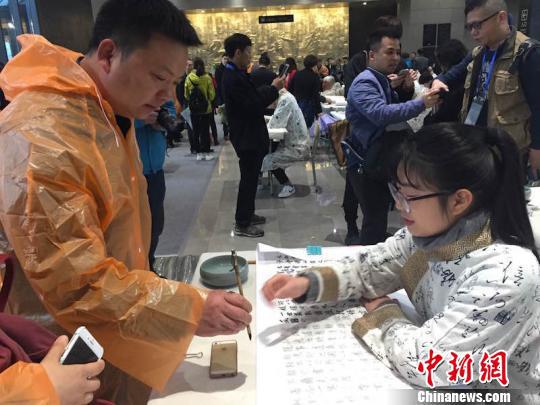 活动现场书法爱好者向书法学生求教　陈洁　摄