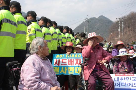 3月29日白天，村里的奶奶们坐在卡车欲经过的道路上