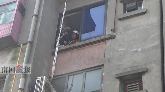老太被楼顶的消防员拉到自家窗外后,屋内的消防员成功将她救回屋内。通讯员 唐恒 摄