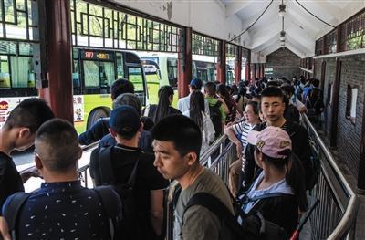 “五一”假期首日，游客排队乘坐返城的公交车。新京报记者 李强 摄