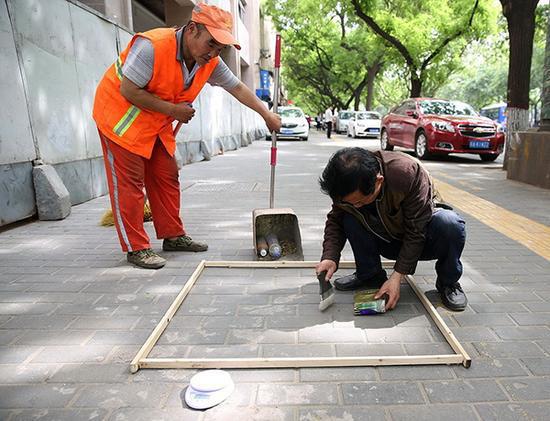 2017年4月24日，在西安市和平路，检查人员在一个标准的一平方米范围内用毛刷收集地表和砖缝中尘土。资料图