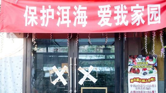 一家关停的餐馆还未撤下门口的广告牌 摄影/吴军