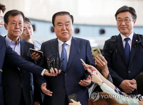  5月17日，在金浦机场，韩国总统文在寅派往日本的特使、前国会副议长文喜相（中）启程赴日前接受记者采访。来源：韩联社。