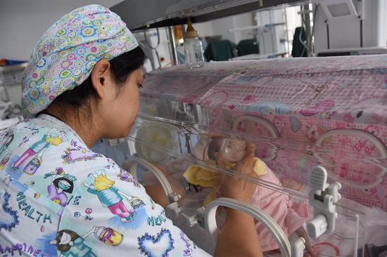(图为陕西省第四人民医院护士正用母乳库的母乳喂一早产儿。新华社记者姜辰蓉摄)