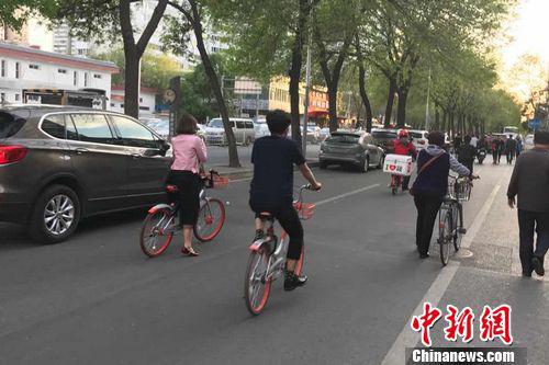 北京街道上正在骑共享单车的人。程春雨 摄