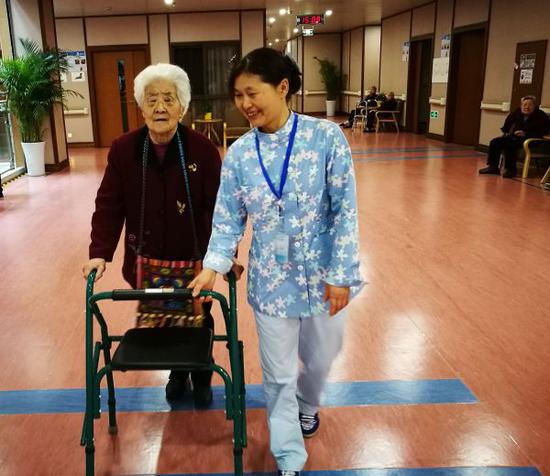 资料图片：护理员正扶持老人进行行走康复训练。新华社记者 董小红 摄