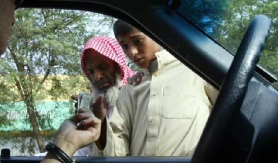 在沙特利雅得，一名司机给乞丐钱。（图片来源：法新社）