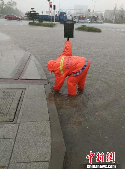 环卫工人在雨中忙着去除排水口里的落叶和堵塞物。　城管供图