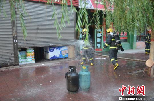 10日下午,山西太谷一饭店厨房失火,一具液化气罐被大火吞没烧成了黑色。消防官兵冒着生命危险冲进火海关闭阀门、拎出气罐,阻止了一起爆炸事故。 消防供图 摄