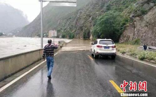 四川某地道路被淹没交通中断,过往路人和车辆通行受阻。 钟欣 摄