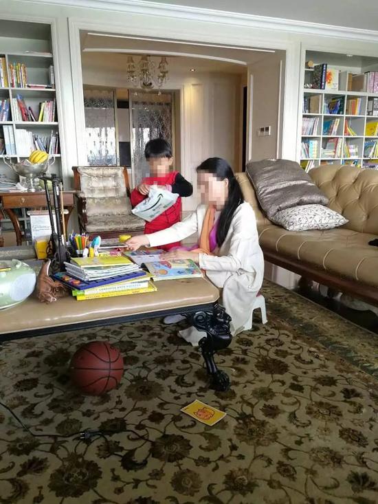 朱小贞和小儿子在客厅里，背后书架为起火点。（受访者供图）