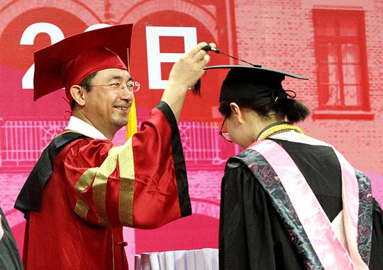校长熊思东在学位授予仪式上为毕业生帽扶正流苏。