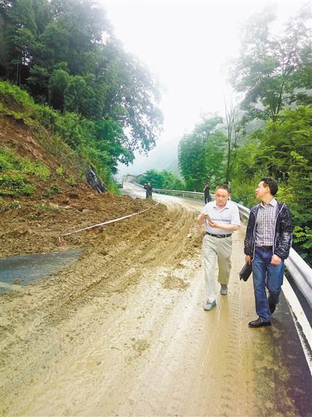  一场暴雨后，何国权（左）与同事一道巡查公路受损情况。