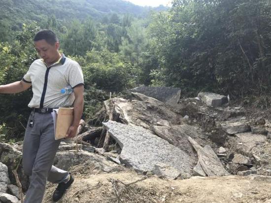 村民在被挖掘的化石坑旁走过。 汹涌新闻记者 谢寅宗 摄
