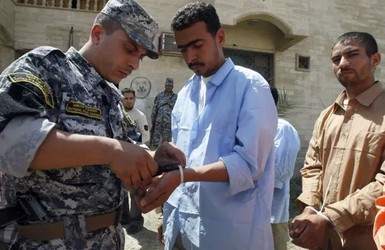2009年4月13日，在伊拉克首都巴格达，一名伊拉克警官打开一名囚犯的手铐。