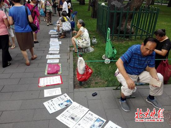 有的坐在小板凳上，面前摆着一块纸板；有的捧着纸板。  本文图片均为北京晚报 图