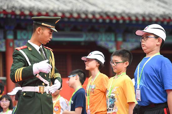 来自2017《基本法》香港校际问答比赛学习团的百名小学生，于7月9日至14日在北京参观访问。 图为：7月11日，天安门国旗护卫队战士在给香港小学生讲解站姿要领。 新华社 图