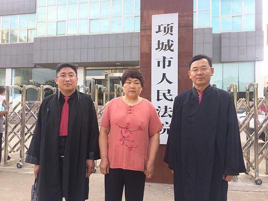7月14日庭审前,李桂英和代理律师在法院门口合影。 家属供图