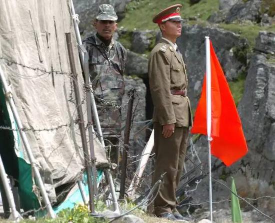 ▲資料圖片：2006年7月5日，在中印邊境錫金段乃堆拉山口，一名中國邊防軍人（右）與一名印度邊防軍人隔著邊界的鐵絲網值勤。