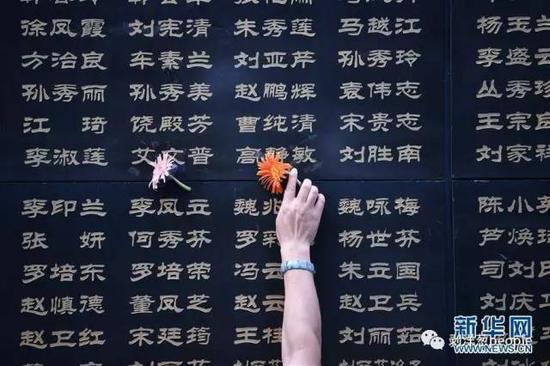 7月28日，唐山大地震41周年纪念日。一位唐山市民将鲜花粘附在遇难亲人的名字旁。