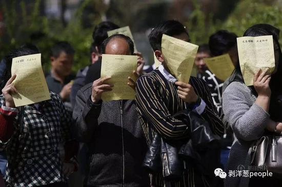 民众在阅读“远离传销，共建协调”宣传单。