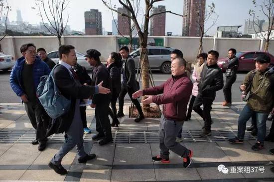 ▲2016年12月22日，被判无罪的黄志强(穿红黑运动鞋者)走出法院和状师握手。    新京报记者 王嘉宁 摄