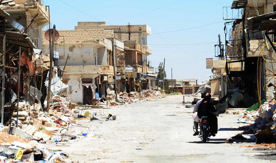 7月29日，叙利亚阿勒颇省马斯卡纳县，一名当地男子骑着摩托车经过一条被战争摧残的败破街道。6月初，马斯卡纳被叙利亚政府军收复，成为阿勒颇省最后一个被解放的极端分子据点。（新华社发）