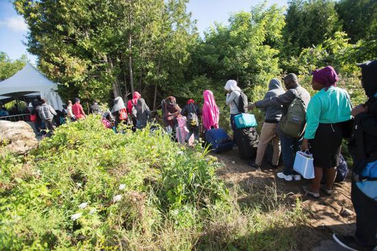图为逃离美国的难民在美加边界排队等候进入加拿大