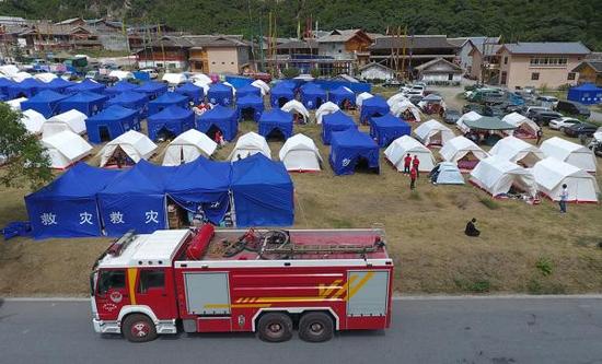 九寨沟景区荷叶寨的灾民安置点前,驻守着消防救援抢险车,随时应对安全救援任务。澎湃新闻记者 赵昀 图