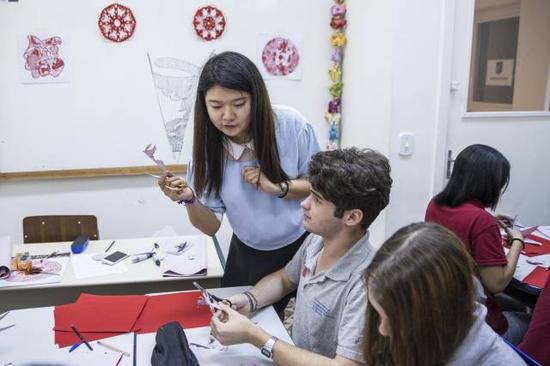 8月11日，在巴西尼泰罗伊市的若阿金·戈麦斯·德索萨葡中双语学校，中国志愿者老师王岩在课堂上教学生剪纸。（新华社记者李明摄）
