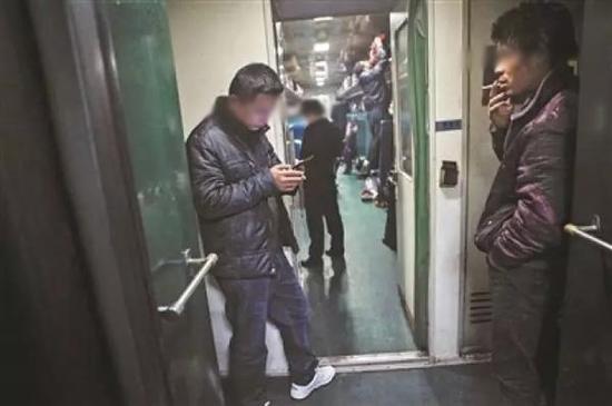 乘客在普通列车的车厢连接处抽烟。