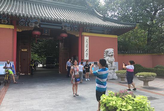 8月14日，游客在上海交通大学大门口留影。