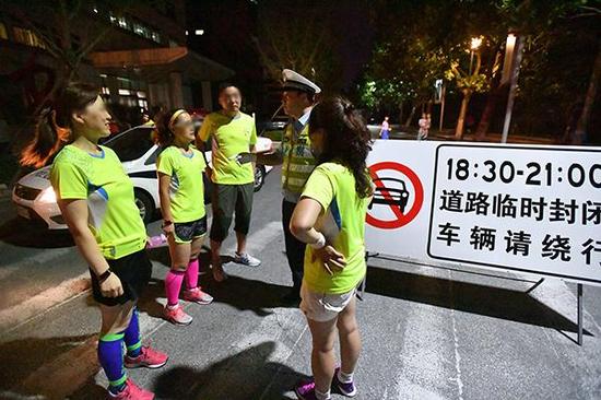 8月25日，青岛，交警提醒“暴走团”市民应该在机动车限行的时间段内上路健身。视觉中国 图