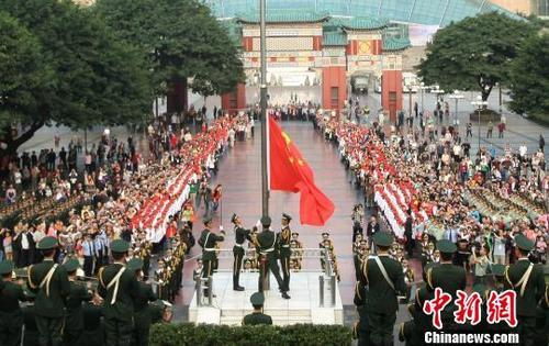 武警官兵升国旗,市民们行注目礼、高唱国歌。陈超 摄