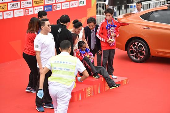 去年北京马拉松冠军被搀扶领奖，合影时晕倒。