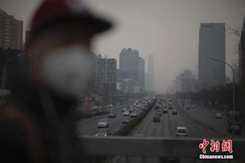 资料图:北京市民在雾霾中出行。 中新社记者 刘关关 摄