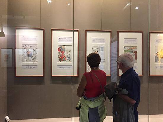漫展吸引了两位外国游客,一旁有导游向他们诠释漫画主题。