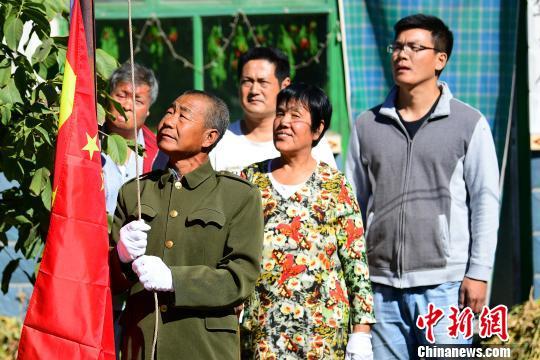 10月1日，河北省廊坊市安次区调河头乡朱官屯村的农民郭庆栋（左二）和老伴马淑敏（右二）在自家院内升起崭新的国旗。　宋敏涛 摄