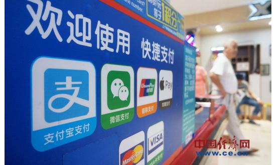 资料图片:2017年9月6日,顾客从杭州一家超市的微信支付、支付宝等非银支付标识前走过。(图片来源:视觉中国)