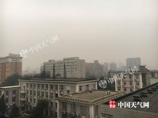 今晨7时左右北京天空阴沉,远处楼房已模糊。