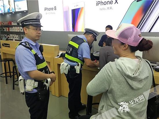 一名民警与消费者沟通，另一名民警向手机店工作人员小霍了解情况。记者 张勇 摄