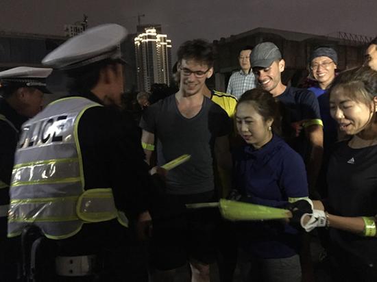 徐汇警方在滨江公园向夜跑市民赠送夜光带，讲解夜间安全知识。澎湃新闻记者 李佳蔚 图