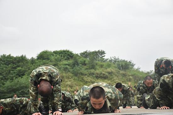 体能训练中,很多战友已经支撑不住,但孔文(中)还在不懈坚持,做好每一个俯卧撑